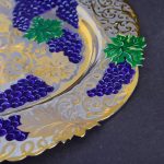 Gold dish with artistic pattern of bunches of grapes