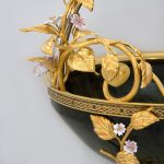 Unusual designer vase with golden leaves and pink flowers.