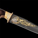 The knife blade is made of a high-carbon alloy composition of metals with a characteristic pattern. The teeth are on the butt. Front side of the blade is decorated with a golden emblem of an eagle. The knife hilt is made of brown resin.