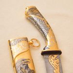 golden handle of a hunting knife with scabbard