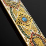 The scabbard is decorated with an ornament with the addition of enamel and gold, as well as cubic zirconias of different colors.