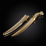 Gold dagger and scabbard with large green cubic zirconia and ornamentation with enamel