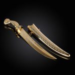 Gold dagger and scabbard with large green cubic zirconia and ornamentation with enamel