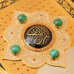 Golden Arabic calligraphy on black enamel decorated with red cubic zirkonia and natural malachite